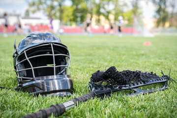 Lacrosse goalie gear on the grass field, with players in the background.