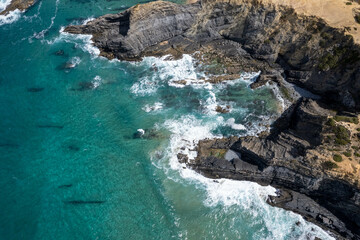 Fototapeta premium View of the rocky coast of the cliff turquoise ocean underwater rocks waves with foam crashing on the rocks