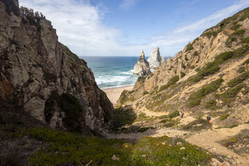 Fototapeta na wymiar Rocky trail leading to a sandy beach with large rocks in the ocean