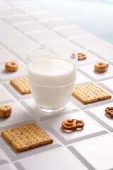 A glass of milk on a white tile and cookies with crackers