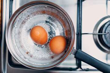 Saucepan stainless steel with boiling eggs breakfast in a water on a gas stove. - 752556227