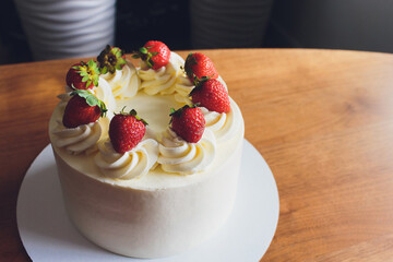 Sweet cake with strawberries on plate on wooden background.