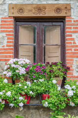 Fototapeta na wymiar Colorful flowers, decorating windows in the village of Santillana del Mar, Spain