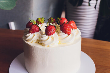 Sweet cake with strawberries on plate on wooden background.
