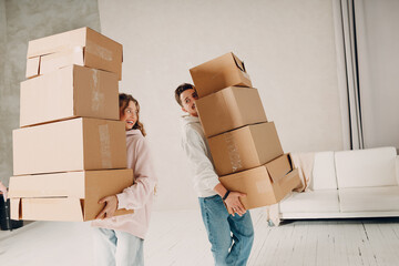 Happy young family couple man and woman moving with cardboard boxes to new estate home apartment.