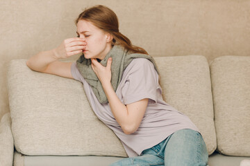 Young woman wearing scarf has flu ill sick disease cold at home indoor on sofa - 752557834