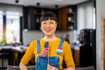 Asian woman standing with an American flag after voting.