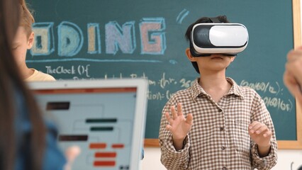 Energetic child wearing Vr headset while enter virtual world at classroom. Student programing...