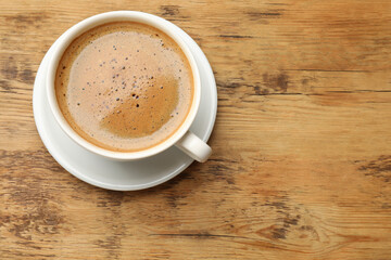 Cup of aromatic coffee on wooden table, top view. Space for text