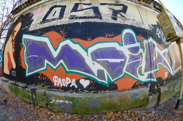Fisheye shot of street art graffiti drawing on wall. Spray art artwork with different colors and outlines. Illegal vandalism concept