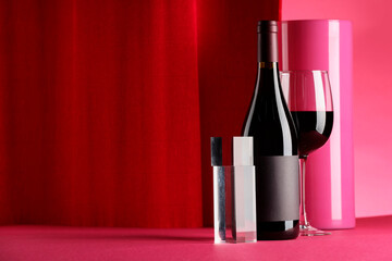 Stylish presentation of delicious red wine in bottle and glass on color background. Space for text