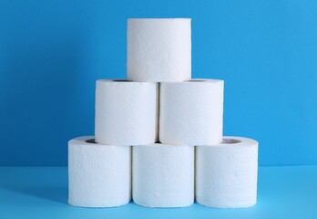 Pyramid of toilet paper rolls on light blue background