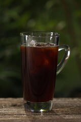 Glass of iced coffee on wooden table outdoors