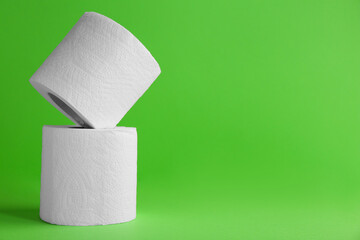 Soft toilet paper rolls on green background, closeup. Space for text