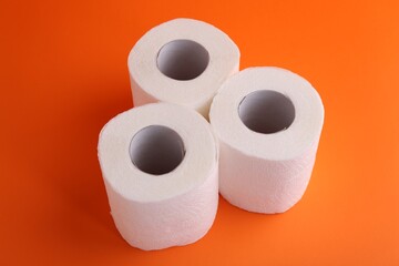 Soft toilet paper rolls on orange background, closeup