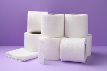 Soft toilet paper rolls on violet background