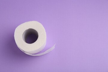 Soft toilet paper roll on violet background, top view. Space for text