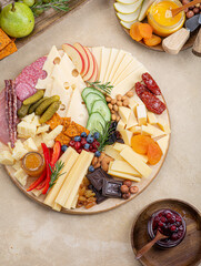 Cheese plate with different types of cheese, fruits, nuts on a light background