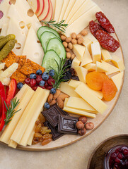Cheese plate with many different snacks. Fruits, berries, crackers, honey, jam lie on the board.