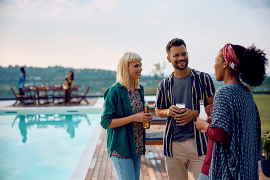 Happy multiracial friends enjoying in conversation by pool.