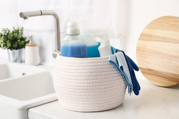 Different cleaning supplies in basket on countertop - obrazy, fototapety, plakaty
