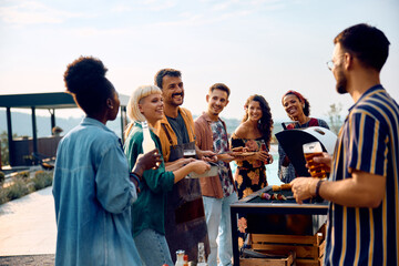 Group of happy friends talking while having barbecue party outdoors.
