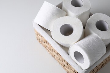 Toilet paper rolls in wicker basket on white table, space for text