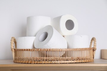 Toilet paper rolls on wooden table near white wall
