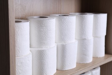 Stacked toilet paper rolls on wooden shelf