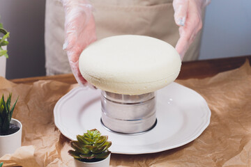 Confectioner makes a wedding cake with confectionery bag at kitchen.