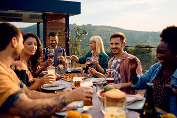 Group of happy friends gathering at dining table on patio.