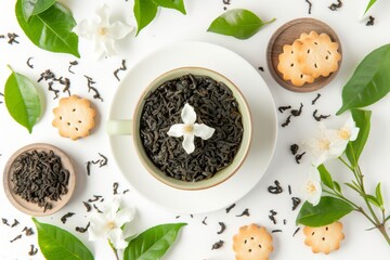 Top view of a tea cup with green tea dried tea leaves fresh jasmine flower and biscuits on a white...