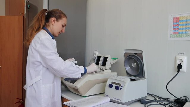 Female scientist with gloved hand putting DNA sample into real-time PCR-cycler