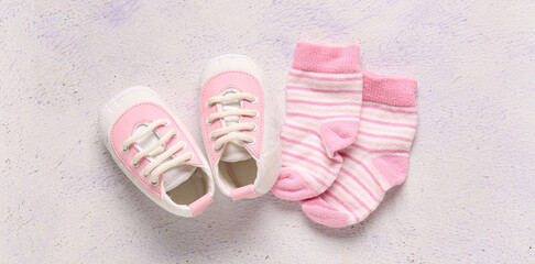 Fototapeta premium Stylish baby shoes with socks on grunge white background