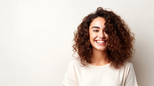 Portrait of a beautiful young woman with curly hair and a bright smile on her face.
