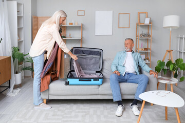 Mature woman packing suitcase for leaving her husband at home. Divorce concept