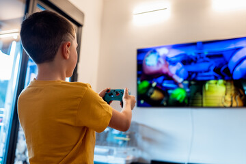 Young boy playing video games on large TV screen