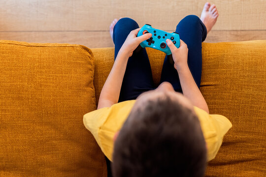 Child engrossed in video game play on sofa
