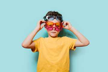 Child with multiple pairs of sunglasses on blue background