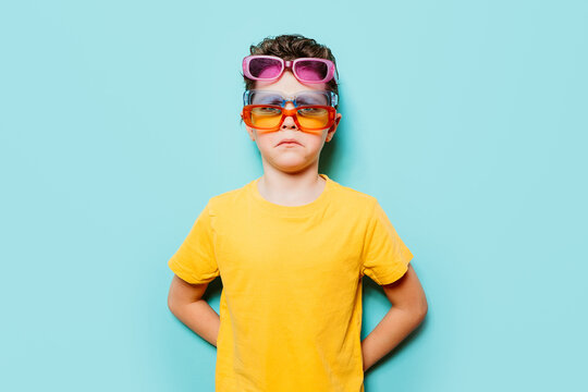 Boy wearing multiple sunglasses against blue background