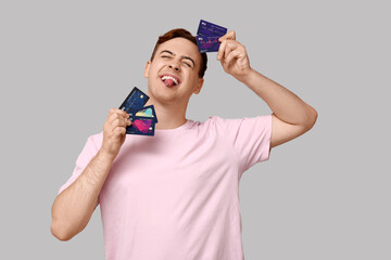 Young man with credit cards on grey background