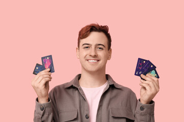 Young man with credit cards on pink background