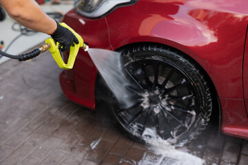 High-pressure washing of car tire and rim at auto detail