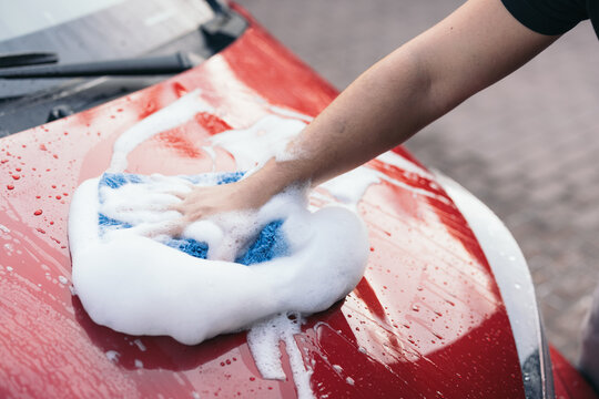 Manual car wash with foam and sponge on red car