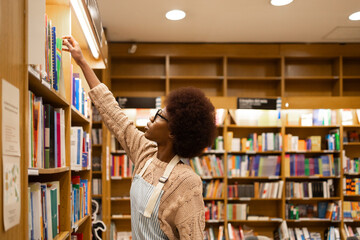 Young African American woman selecting book in library