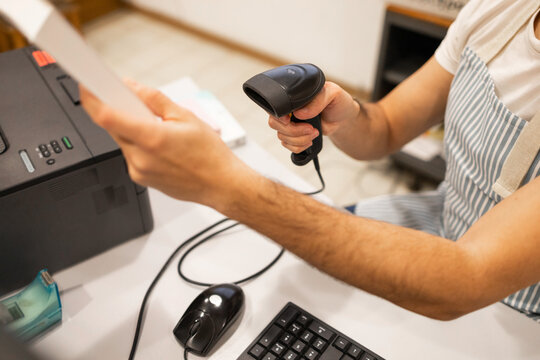 Unrecognizable person Using Handheld Barcode Scanner at Desk