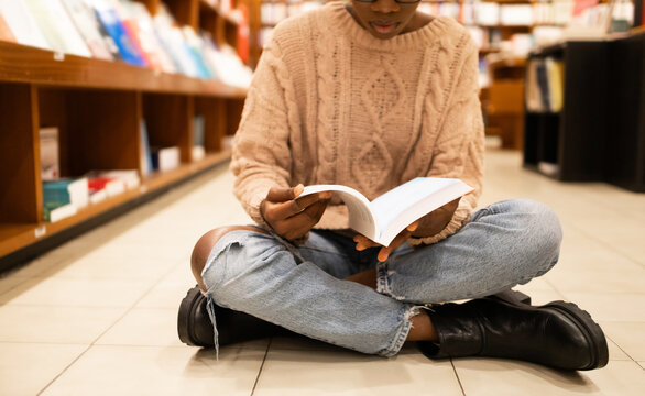 Young African American woman engrossed in reading a book in a library