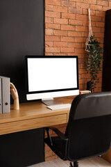 Blank computer monitor with folders on table in modern office