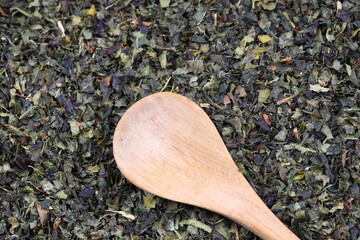 Green  tea with herbs in wooden spoons on a wooden board