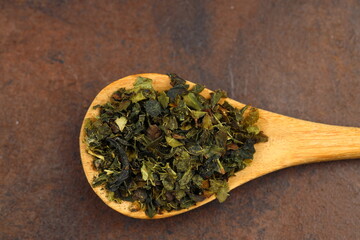Green  tea with herbs in wooden spoons on a wooden board